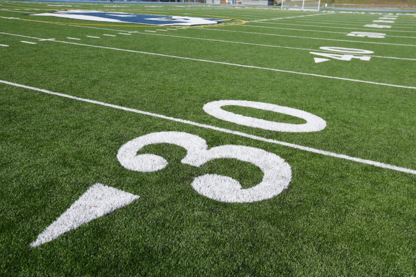 Close-up view of the 30-yard line on a green football field, showcasing white yard numbers and lines. The artificial grass installation by expert Fountain Hills AZ installers is evident, with the field’s logo partially visible in the background.