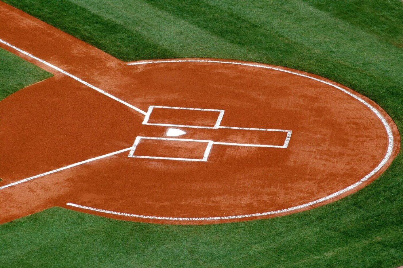 Aerial view of a baseball field’s home plate area in Fountain Hills, showing the batter’s boxes, catcher’s box, and baseline markings on red dirt surrounded by lush artificial grass.